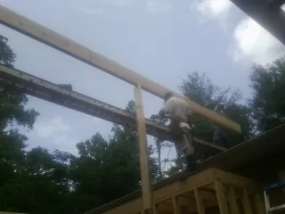 Carpenter setting a ridge beam over a new addition frame — Ice Dam Removal by Roofing Brothers in Mims