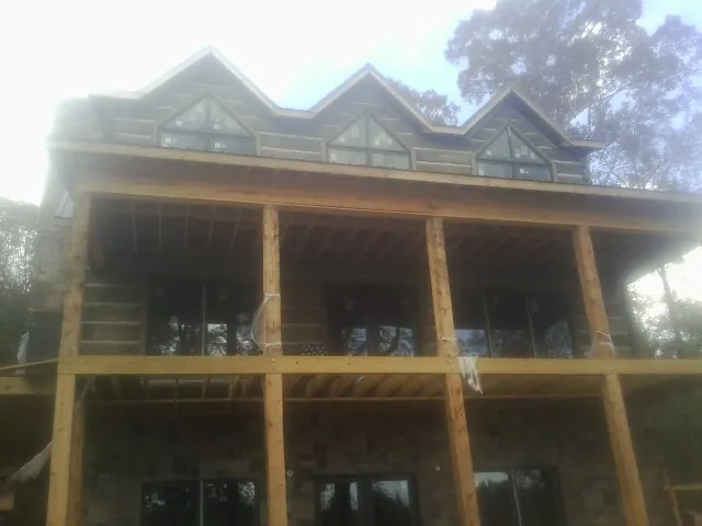 Dormers and porch framing on a large log home under construction — Roof Coating work by our crew in Mims