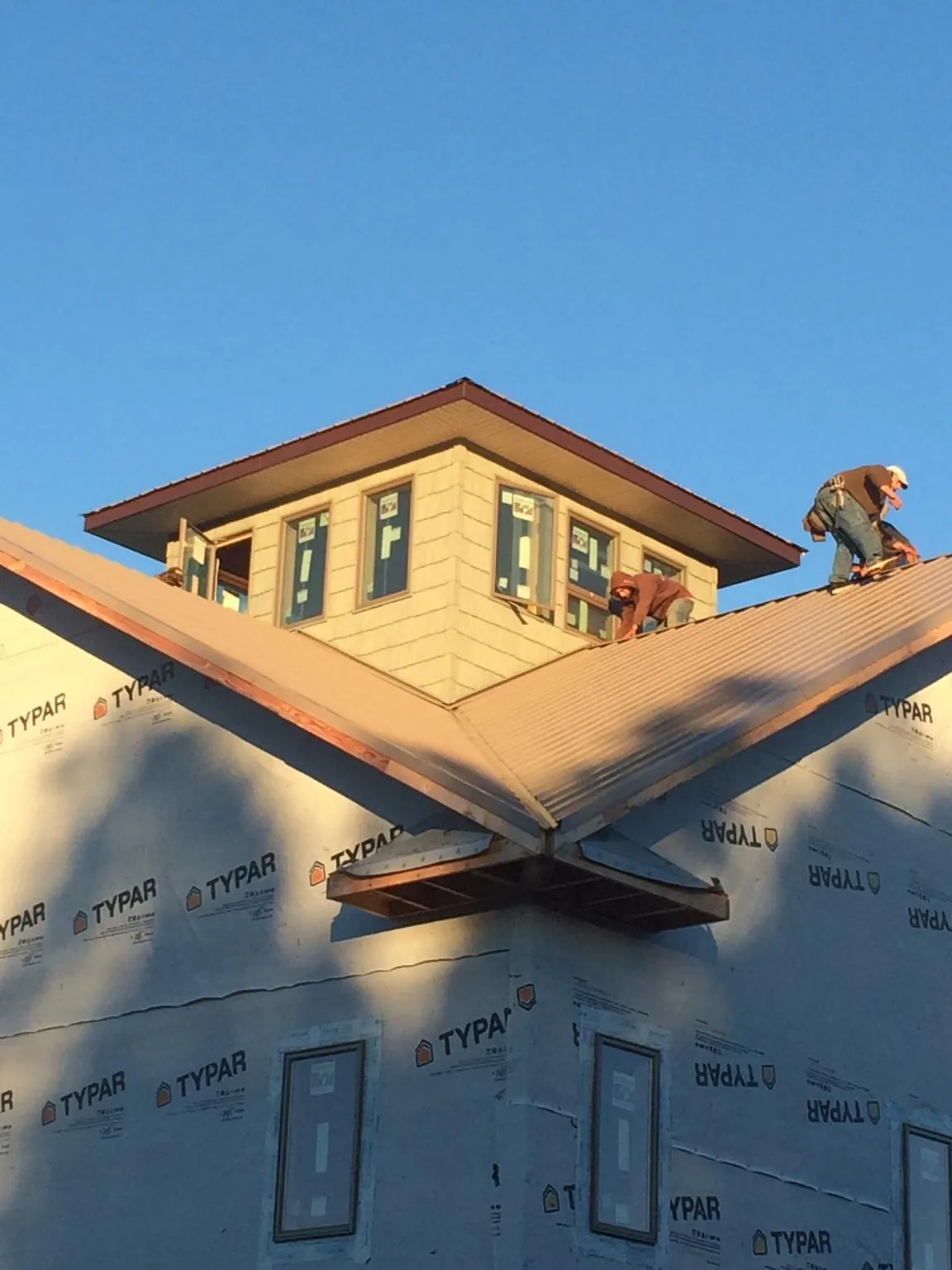 Roofers working around a rooftop cupola on a new metal roof at sunset — Roof Waterproofing in Mims by Roofing Brothers
